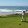 Doug hits his drive with the Pacific in the background.