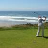Doug hits his drive with the Pacific in the background.